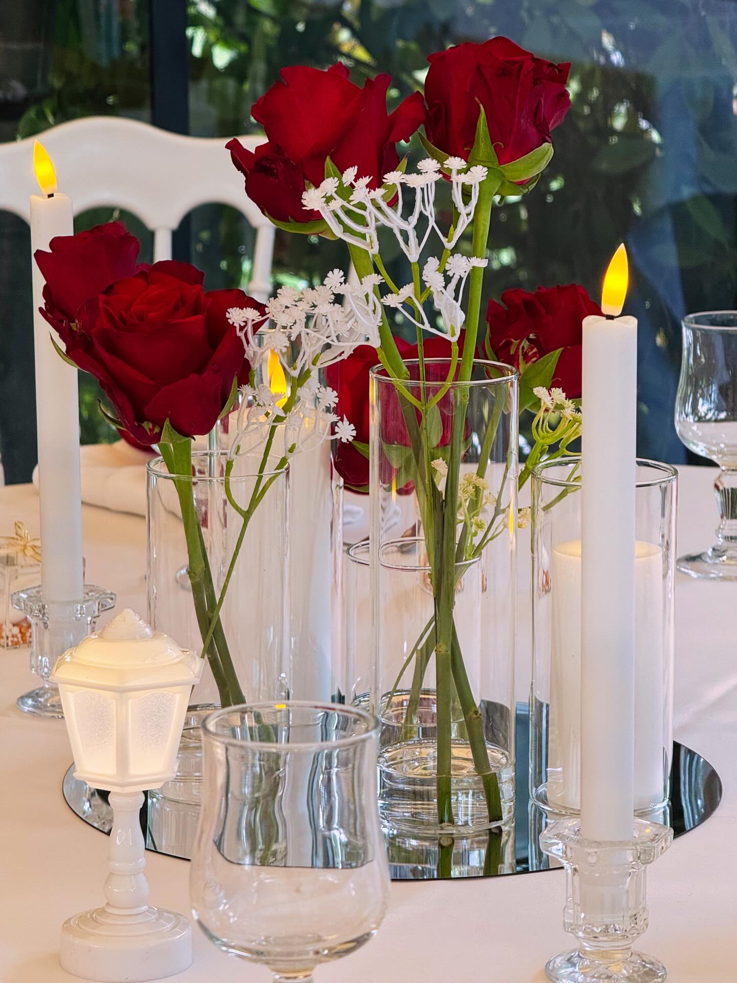Table centerpiece of red roses and candles on a mirror base