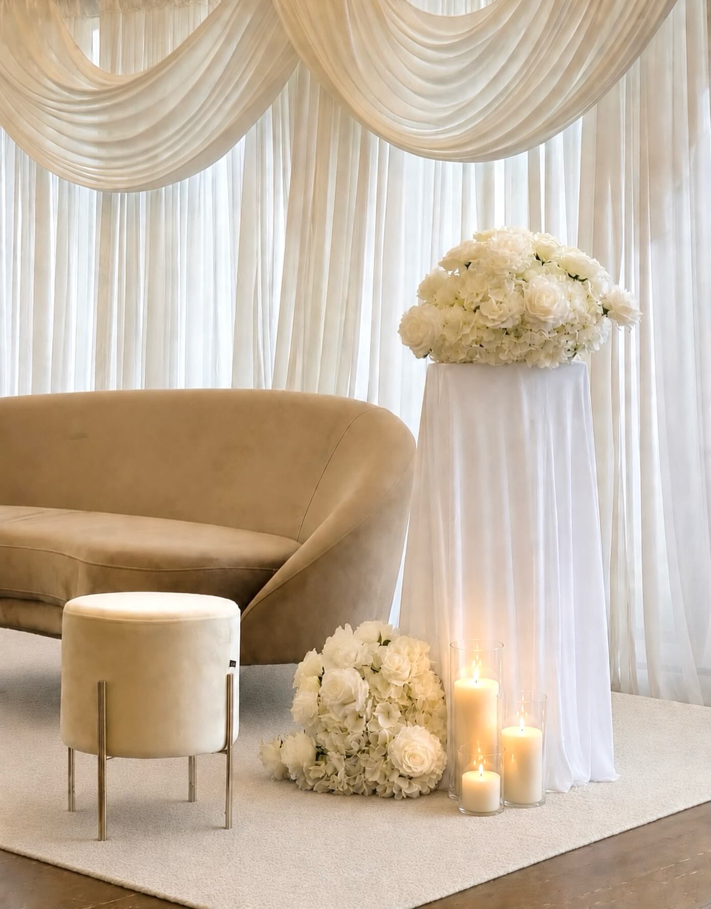 Lounge corner with beige sofa, white floral column and pillar candles