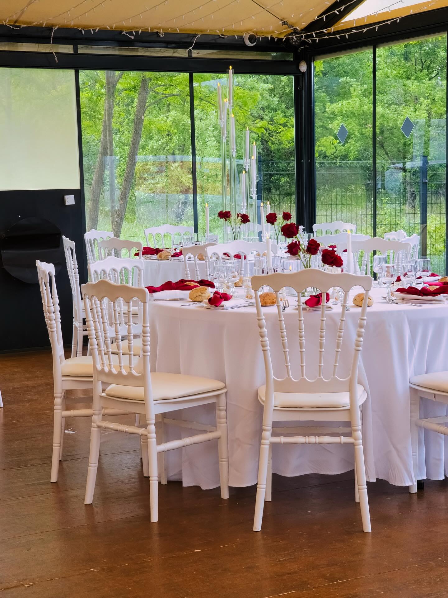 Wedding reception with white Napoleon chairs, round tables and red roses