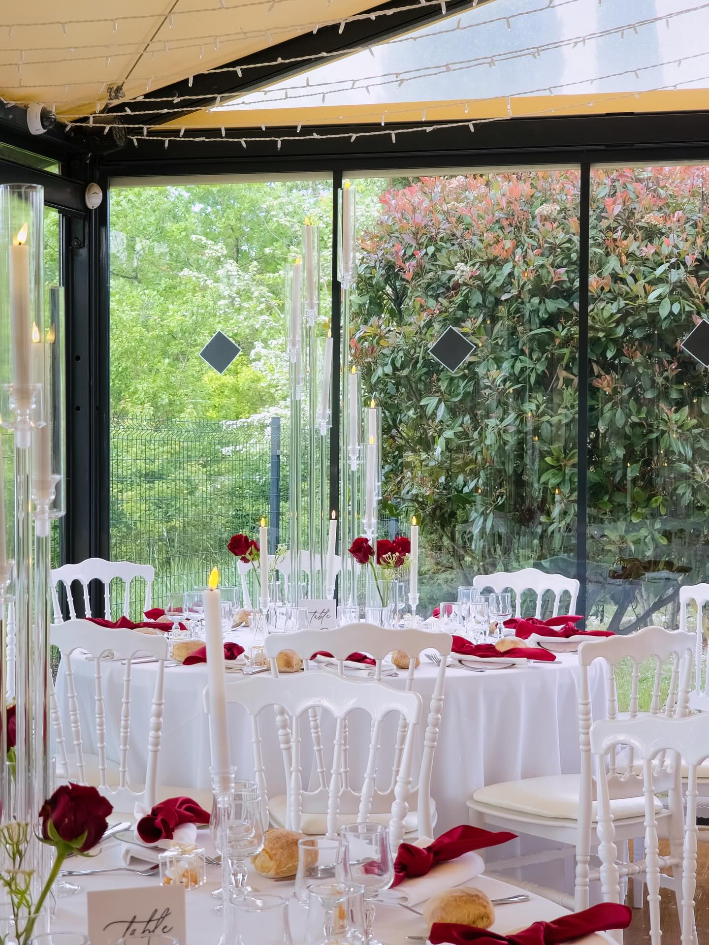 Veranda reception with garden view, red napkins and candelabras
