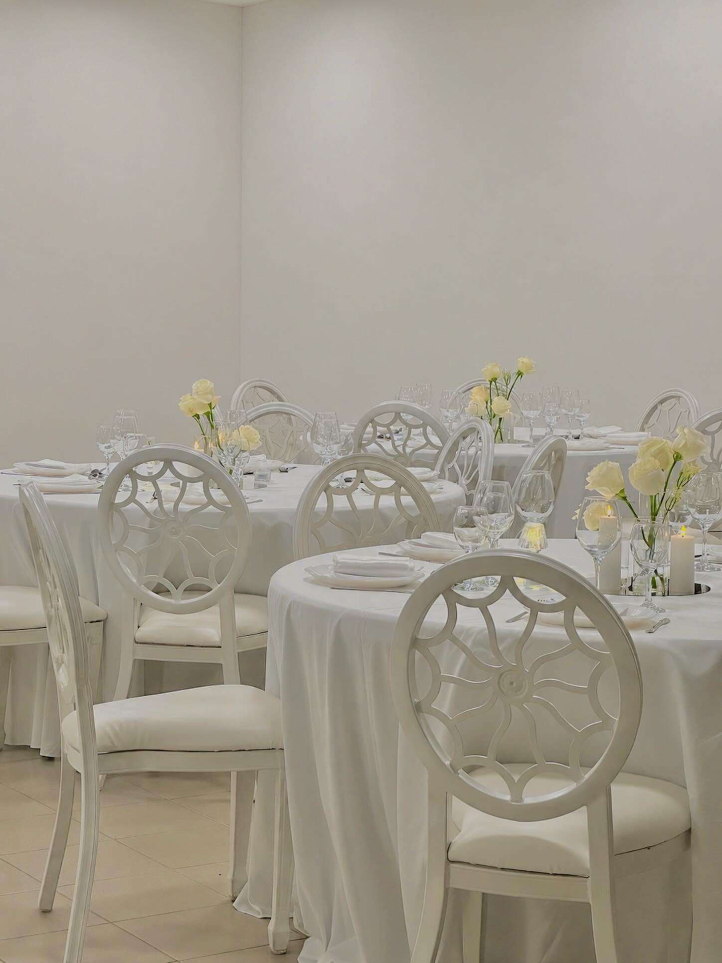 Bright white reception room with openwork designer chairs and white roses