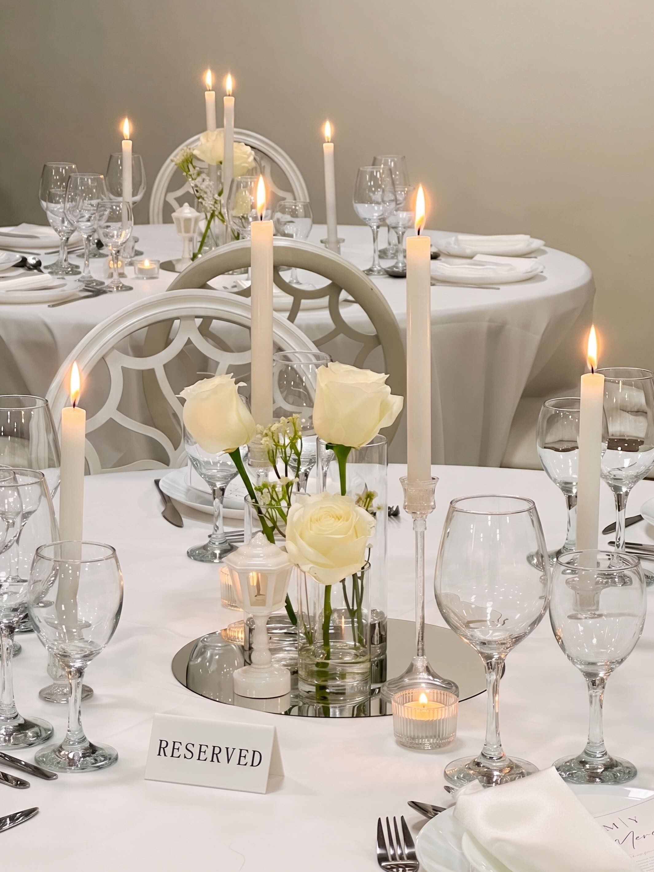 Elegant all-white table setting with white roses and tapered candles